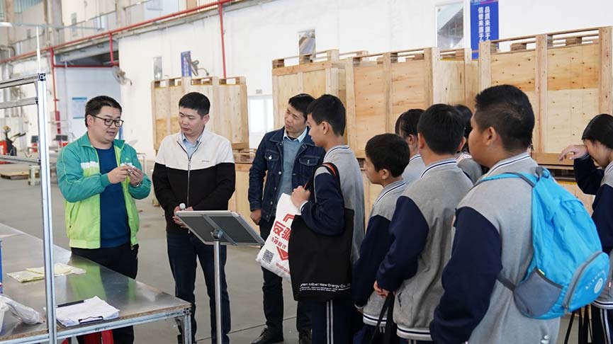 Mibet Energy staff showing a mounting component to students in the workshop